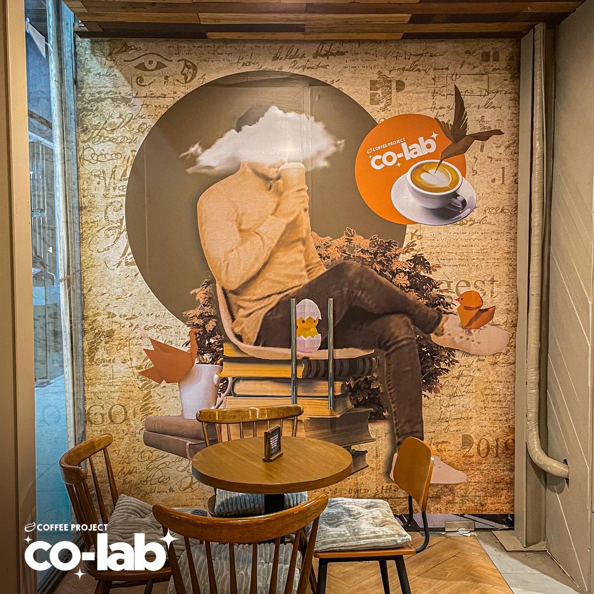 A surrealist mural of a coffee drinker with a cloud for a head anchors a quiet corner, blending literature and art to spark creative inspiration.