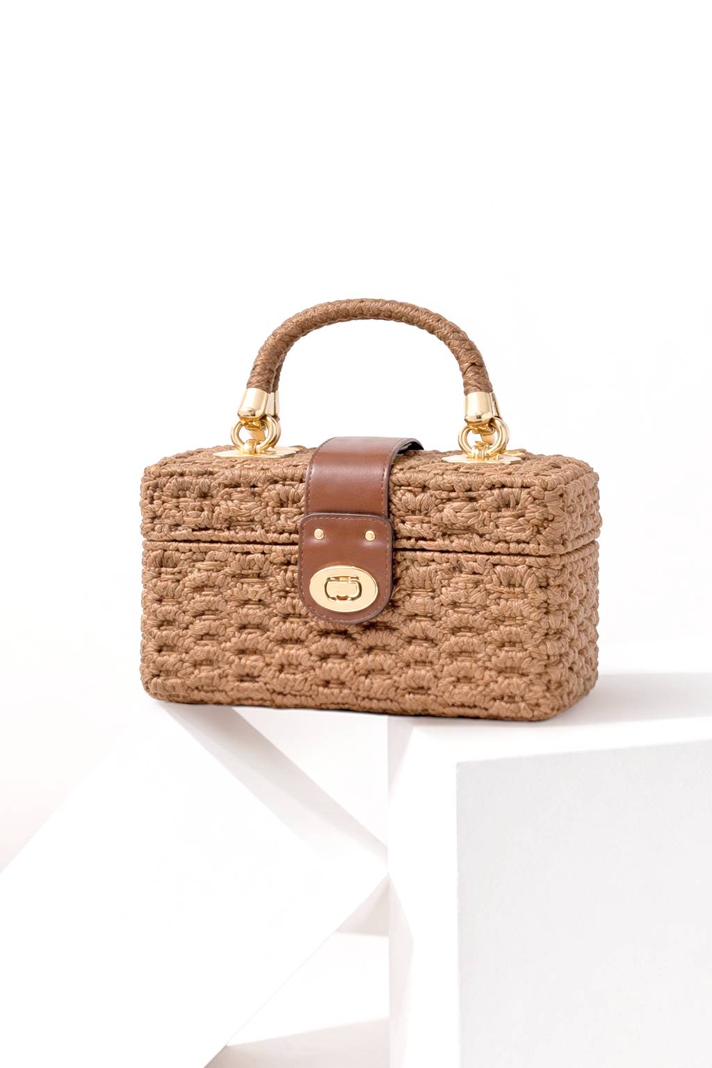 MIKAELA compact boxy bag with a woven exterior, top handle and clasp closure.