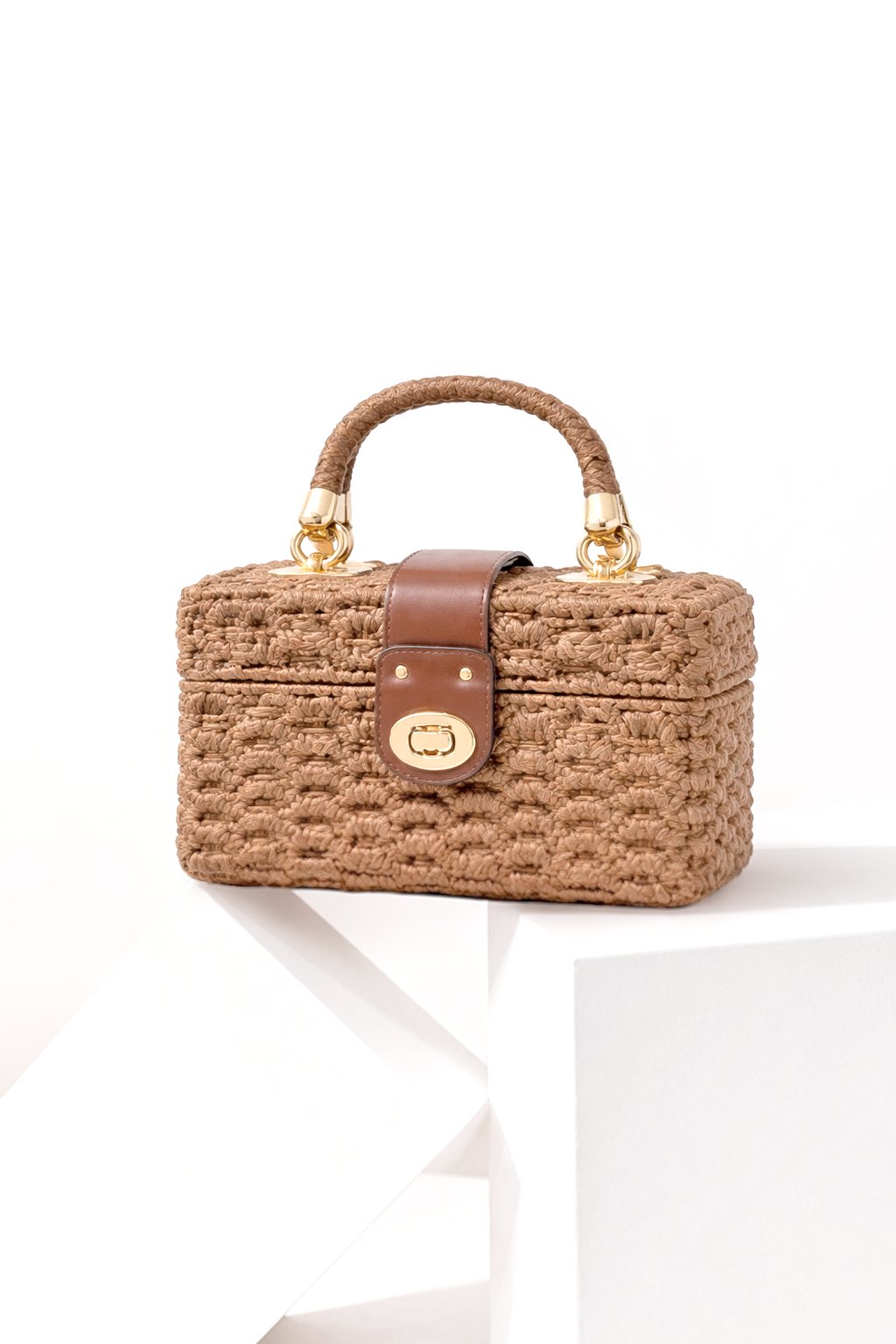 MIKAELA compact boxy bag with a woven exterior, top handle and clasp closure.
