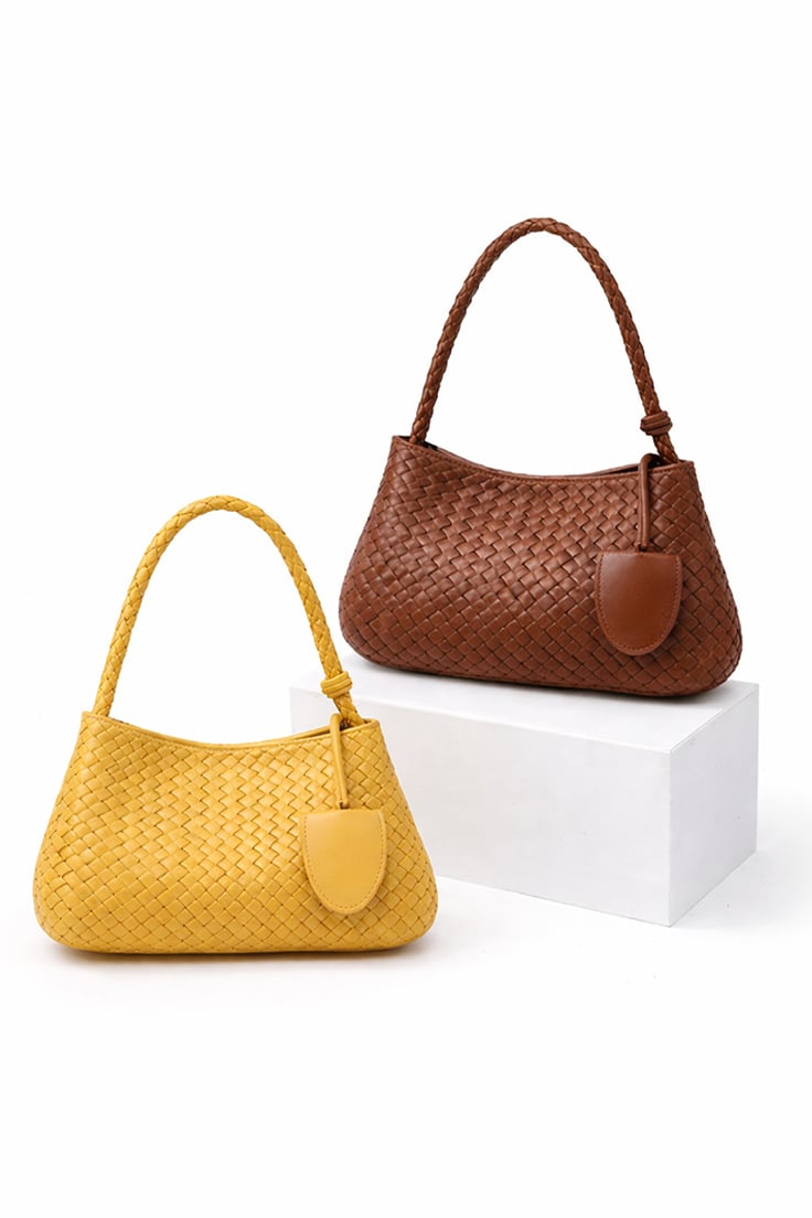 MILEY woven bag with braided handle and subtle tag in rich earth and sunlit hues.