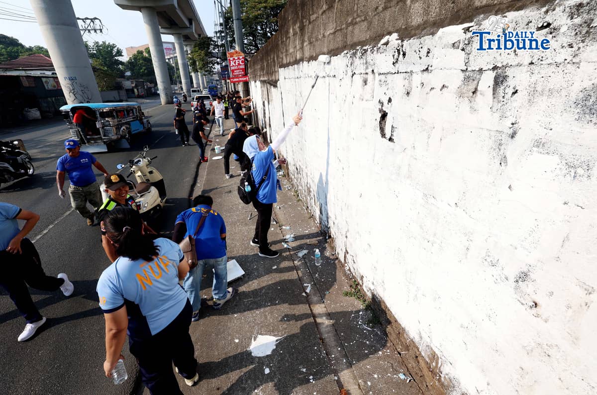 The QCPD and barangay officials cleared posters and other vandalism from a wall along Regalado Highway in Quezon City on Saturday, 18 April 2026, as part of Project Hilamos by the Quezon City government and the QCPD.
