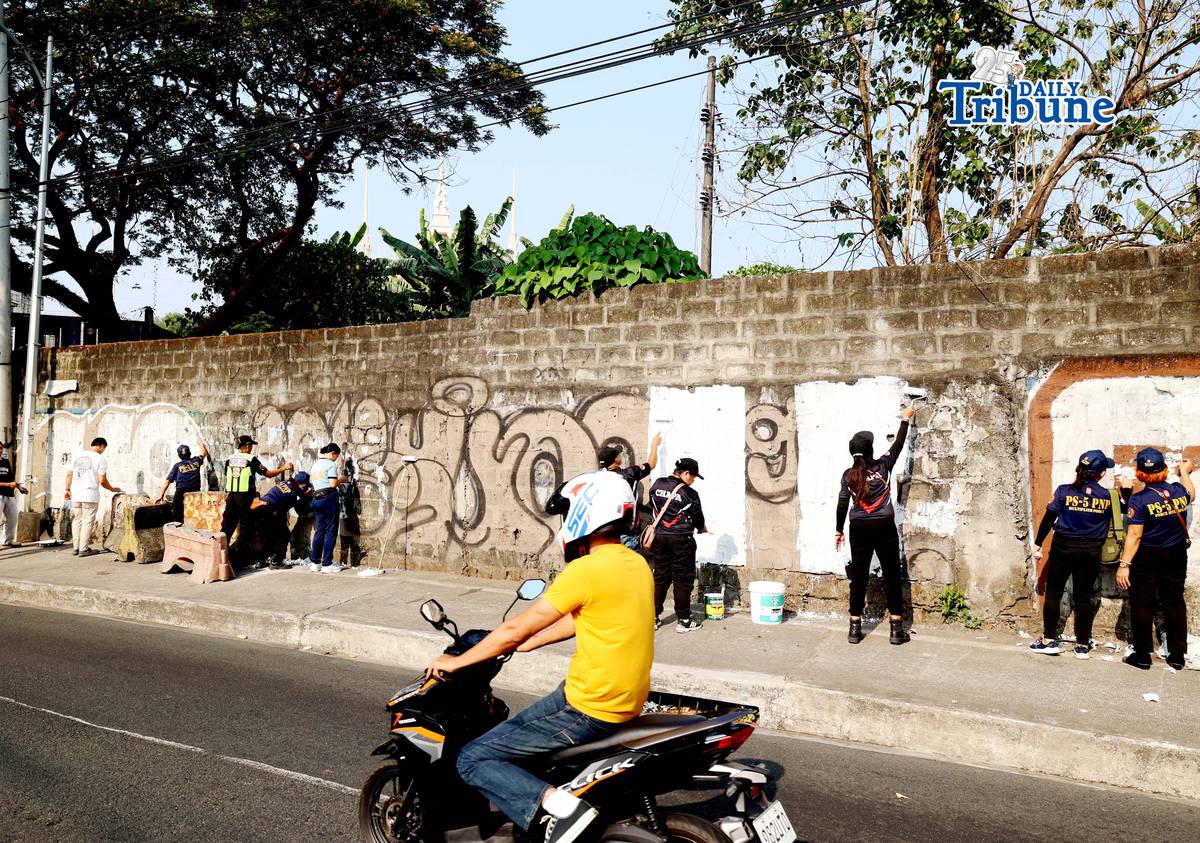 The QCPD and barangay officials cleared posters and other vandalism from a wall along Regalado Highway in Quezon City on Saturday, 18 April 2026, as part of Project Hilamos by the Quezon City government and the QCPD.