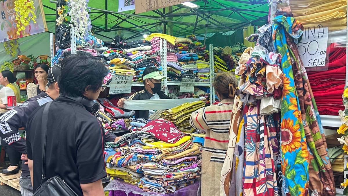 RESIDENTS and tourists inspect stacks of fabric.