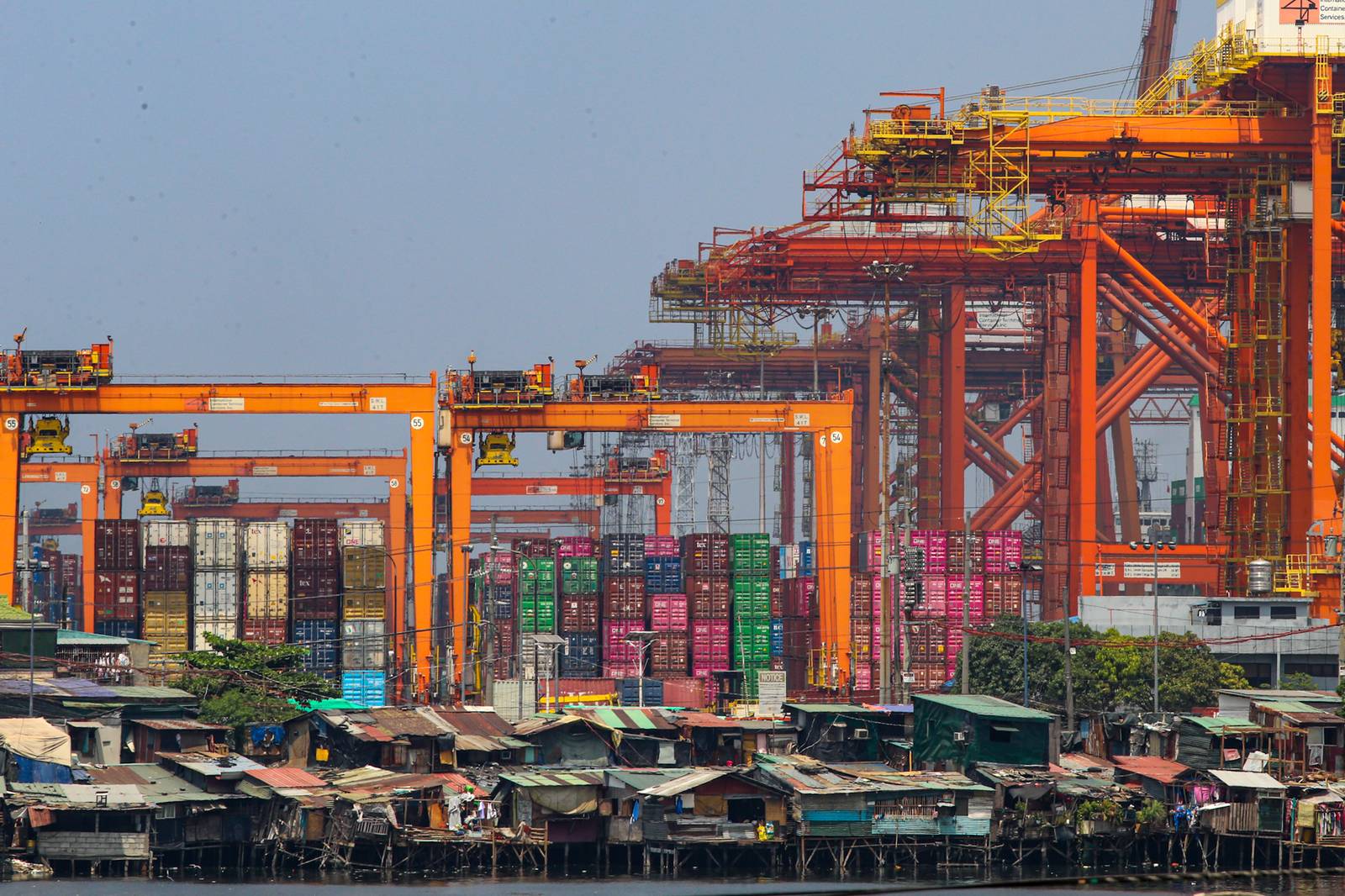 Informal settlements line the edge of the container port area in Manila, as seen from a pedestrian overpass along Mel Lopez Boulevard. A recent study by the government think tank Philippine Institute for Development Studies warns that the current oil crisis could push over 1.3 million more Filipinos into poverty as rising fuel costs lead to an immediate spike in the cost of rice, fish, meat, and vegetables.