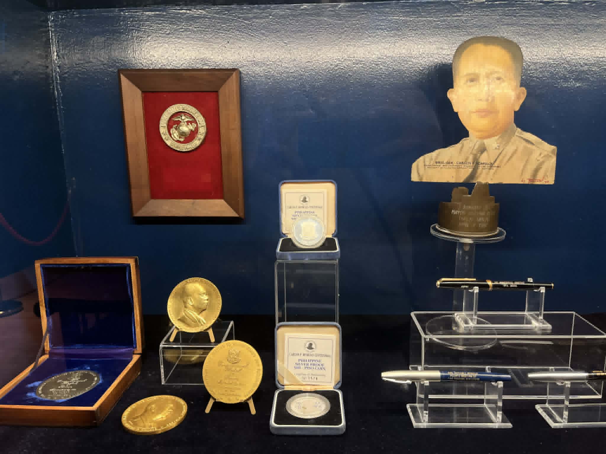 MEDALS, commemorative coins and personal pens on display, reflecting the honors and milestones in Carlos P. Romulo’s distinguished career.