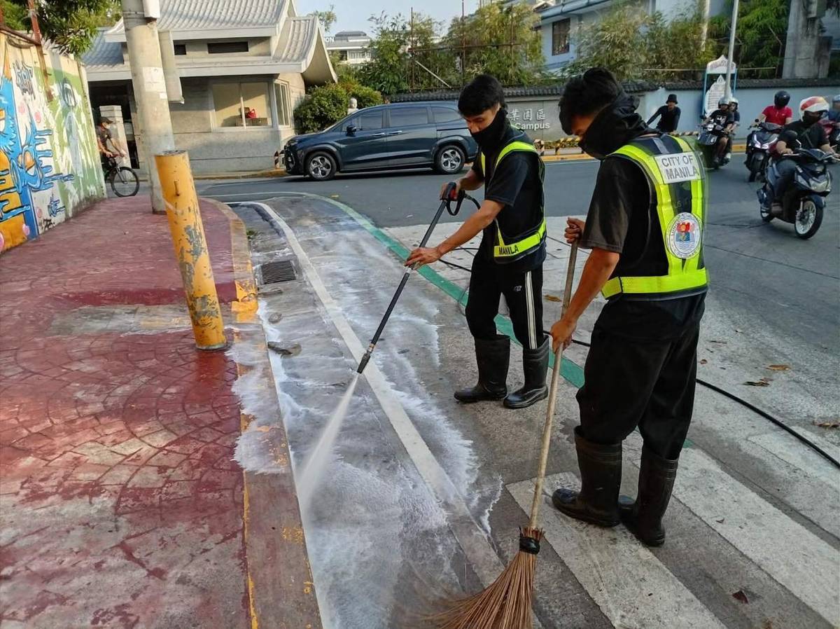WORKERS from the Department of Environment and Public Services conduct sidewalk flushing along Lubiran in Manila to improve public hygiene and safety.