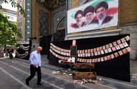 A man walks past images of Iran's late supreme leaders Ayatollah Ruhollah Khomeini (above L) and Ayatollah Ali Khamenei (Above C) next to newly elected supreme leader Mojtaba Khamenei (above R), and photos strung along the wall of children killed on the first day of the war in an alleged US-Israeli missile strike on a school in the southern Iranian city of Minab, outside a mosque in the capital Tehran on 25 April 2026. On 28 February, Israel and the United States launched strikes on Iran, killing its supreme leader and triggering a war that spread across the Middle East.