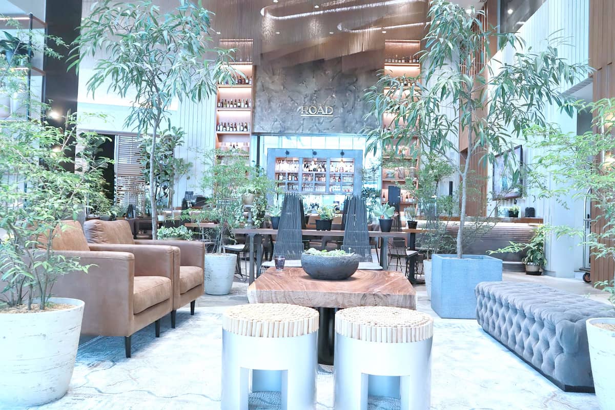 Comfortable chairs and sofas arranged in front of For the Road’s bar, exudes elegance in its muted, earthy neutral colors.