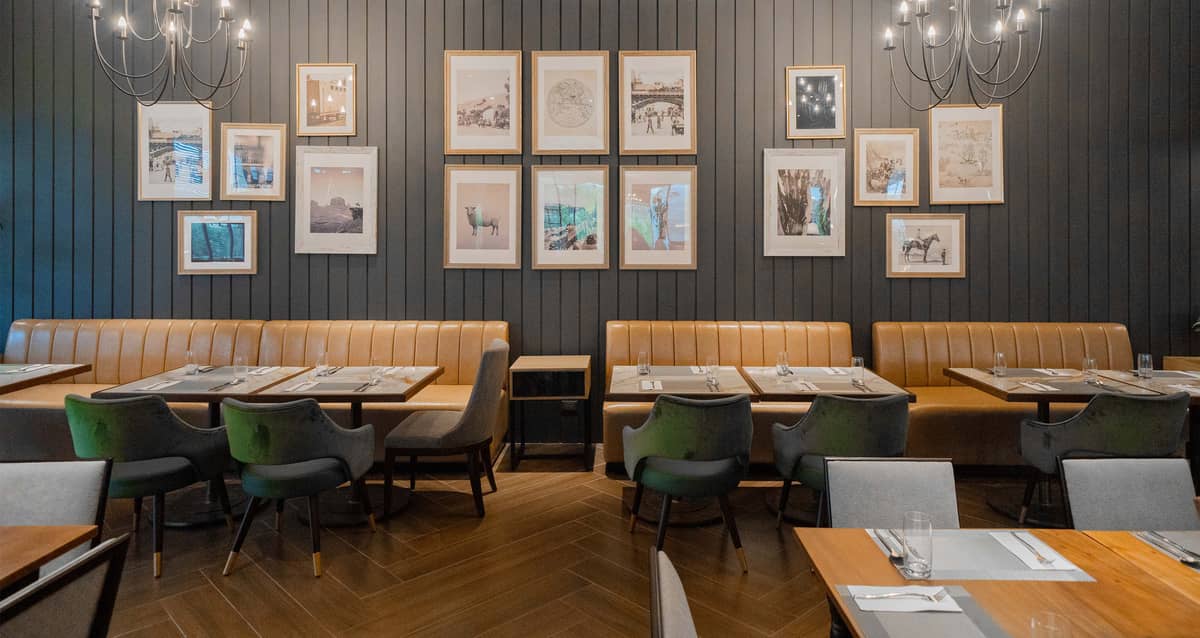 Salt & Fire steakhouse interior features leather banquettes, framed wall art and chandelier lighting.