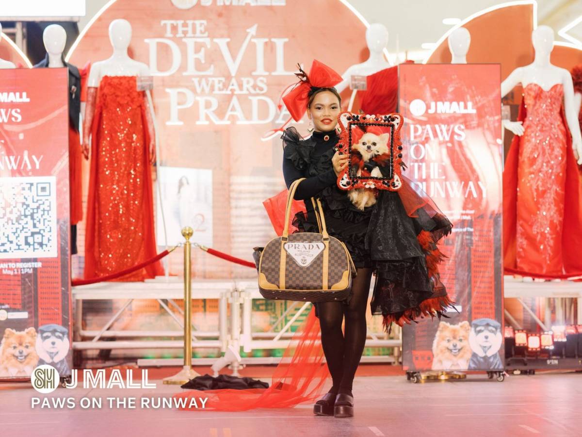 A PARTICIPANT showcases a red-and-black ensemble inspired by The Devil Wears Prada, carrying a small dog in a decorative frame during the 'Paws on the Runway' fashion show at SM J Mall.