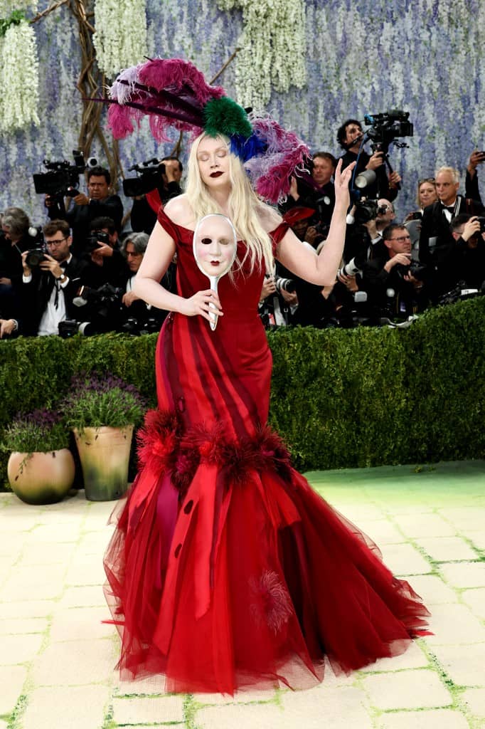 A MASK of her own face was the perfect accessory to actress Gwendoline Christie’s red gown and feathered hat by Giles Deacon.
