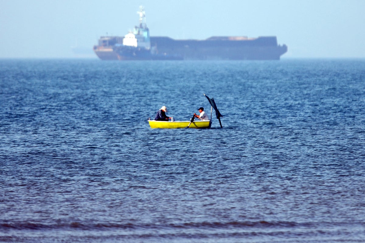 TWO men sitting in a skiff are seen fishing near a vessel anchored in the Strait of Hormuz off Bandar Abbas in southern Iran.