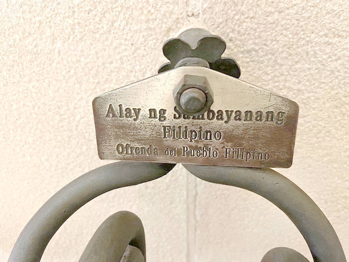 BRASS inscription above a La Sagrada Familia holy water font stating that the clam shells have been donated by the Filipino people.