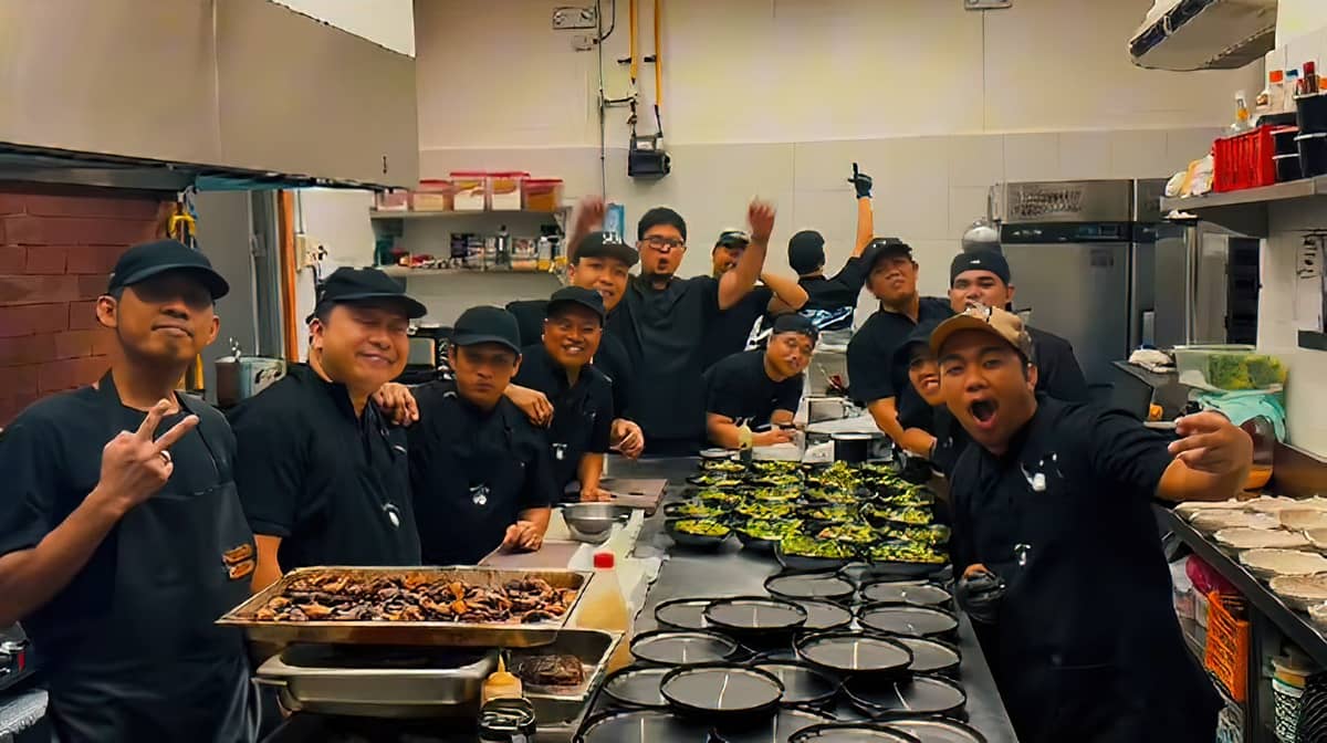 A CHEERFUL kitchen crew prepares dishes with energy and camaraderie