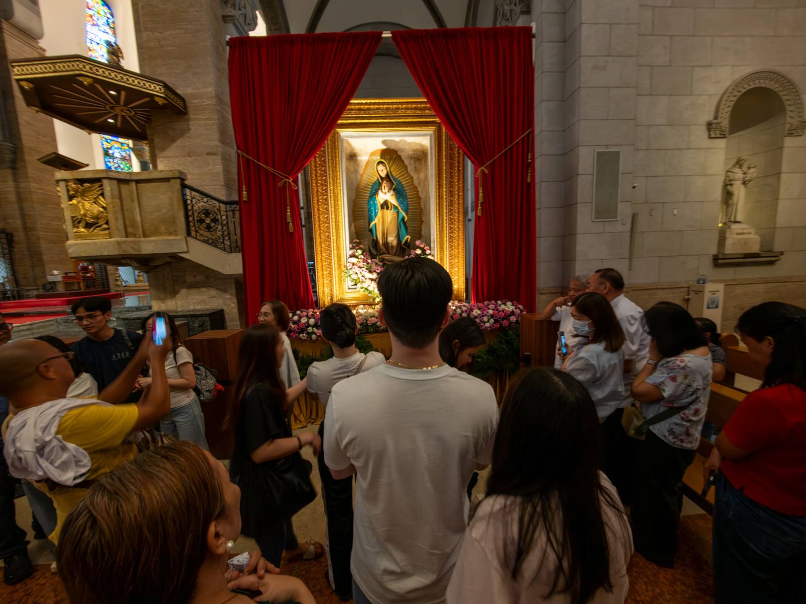 Catholic devotees line up before the images of Our Lady of Guadalupe and St. Juan Diego at the Manila Cathedral in Intramuros, Manila on 14 June 2026. The replica, sent to the Philippines from Mexico, will remain at the cathedral until 18 June before traveling to churches across Luzon, Visayas, and Mindanao until December 2026.