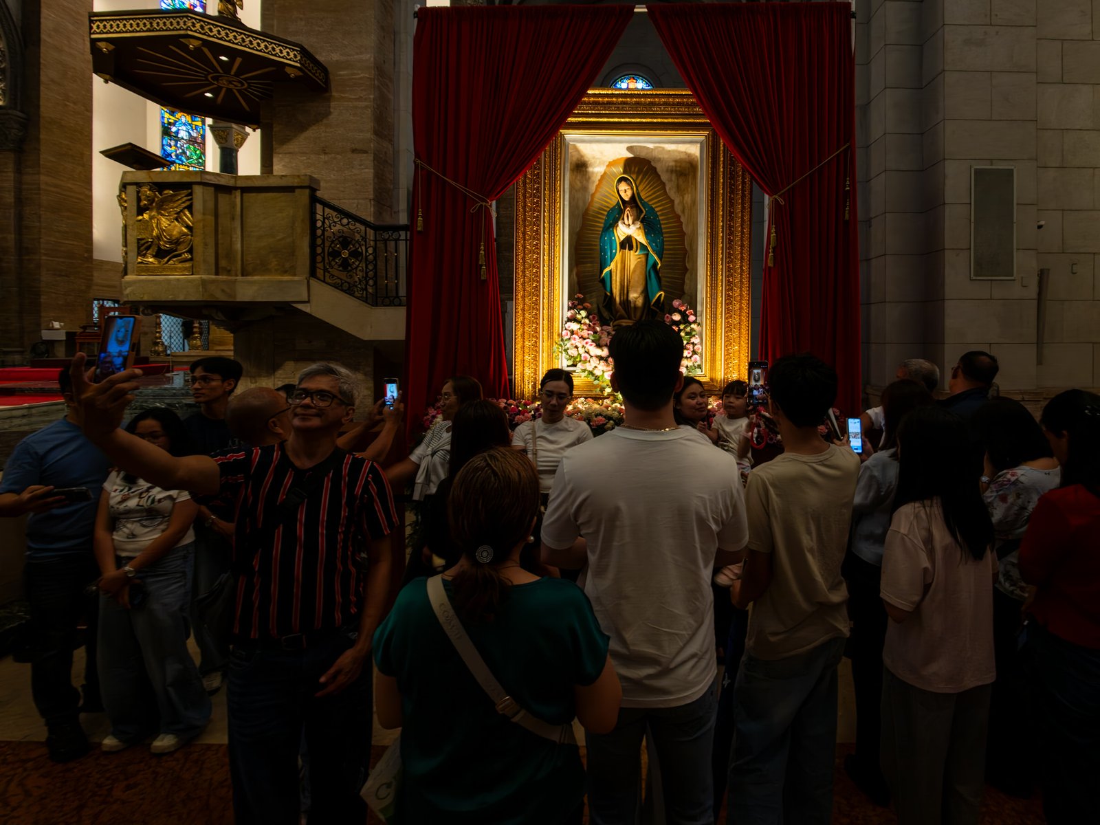 Catholic devotees line up before the images of Our Lady of Guadalupe and St. Juan Diego at the Manila Cathedral in Intramuros, Manila on 14 June 2026. The replica, sent to the Philippines from Mexico, will remain at the cathedral until 18 June before traveling to churches across Luzon, Visayas, and Mindanao until December 2026.