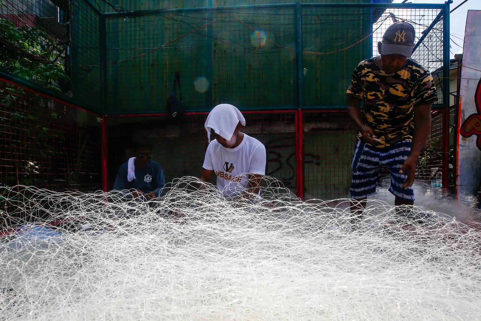 Fishermen repair and assemble nets at a neighborhood basketball court in Navotas City on Saturday, 20 June 2026, as they prepare for their next fishing trip in municipal waters.
