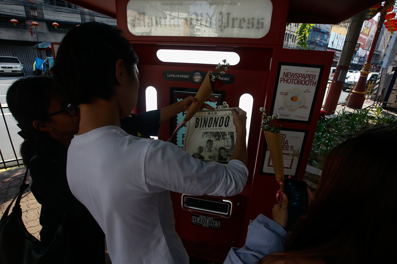 Tourists line up for a photo session at a booth in Plaza San Lorenzo Ruiz in Binondo, Manila on Saturday, 20 June 2026. The photo booth, which prints a vintage-style newspaper alongside a downloadable digital copy, is becoming a popular destination for Binondo-goers.