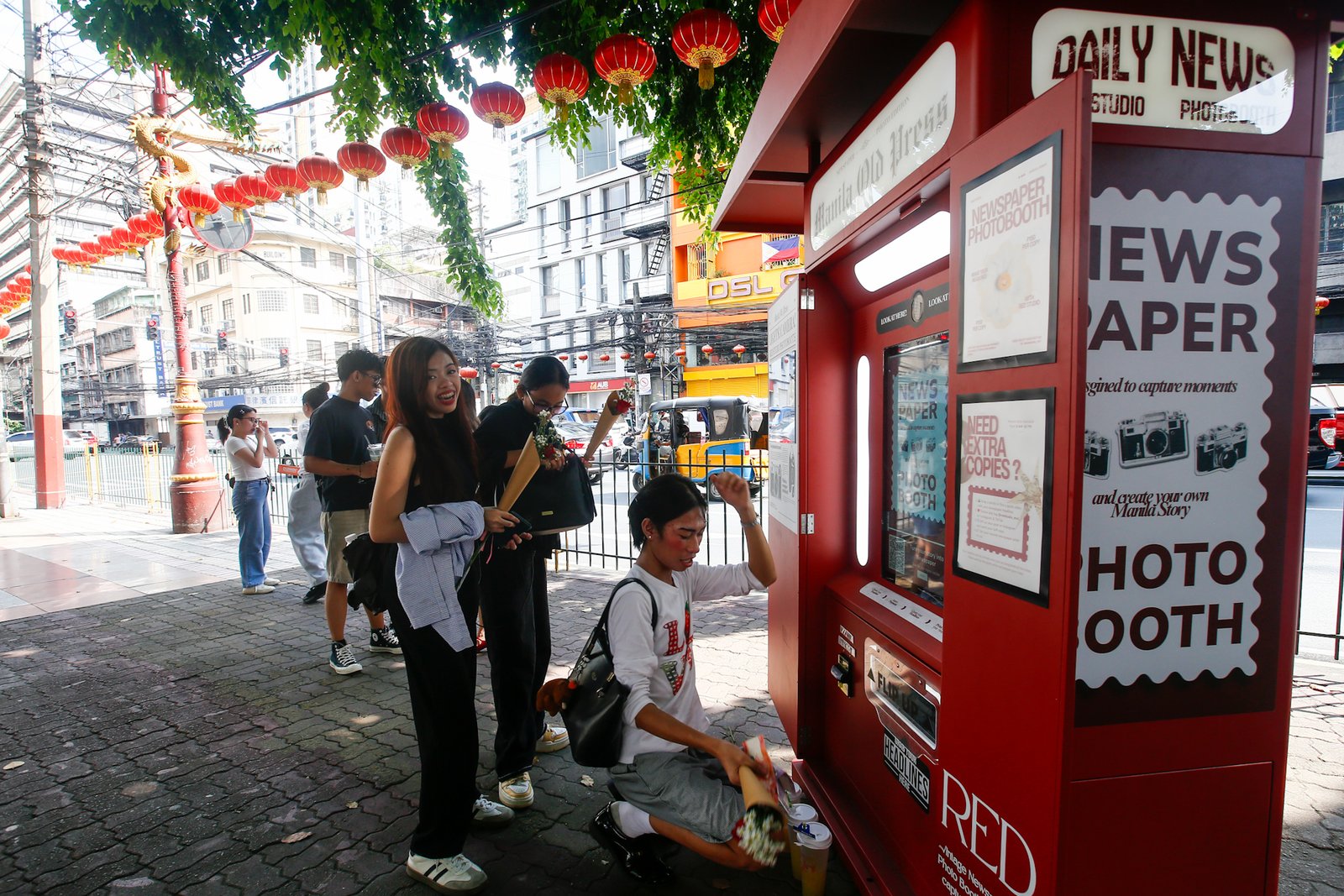 Tourists line up for a photo session at a booth in Plaza San Lorenzo Ruiz in Binondo, Manila on Saturday, 20 June 2026. The photo booth, which prints a vintage-style newspaper alongside a downloadable digital copy, is becoming a popular destination for Binondo-goers.