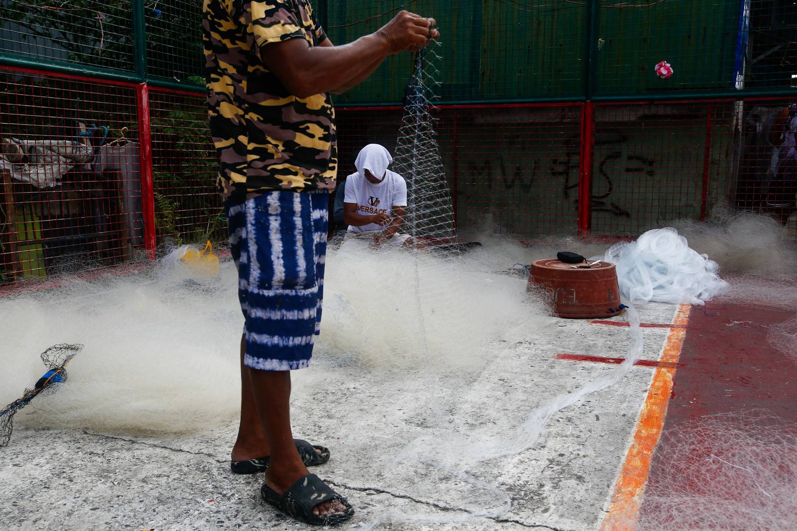 Fishermen repair and assemble nets at a neighborhood basketball court in Navotas City on Saturday, 20 June 2026, as they prepare for their next fishing trip in municipal waters.
