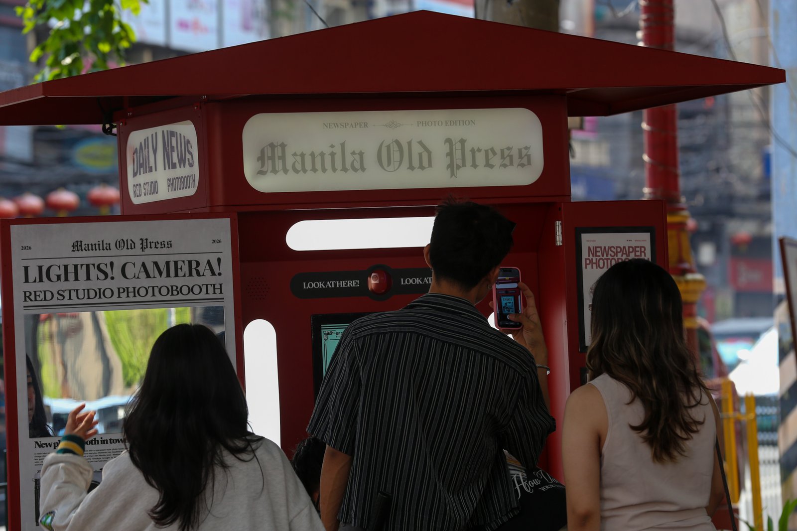 Tourists line up for a photo session at a booth in Plaza San Lorenzo Ruiz in Binondo, Manila on Saturday, 20 June 2026. The photo booth, which prints a vintage-style newspaper alongside a downloadable digital copy, is becoming a popular destination for Binondo-goers.