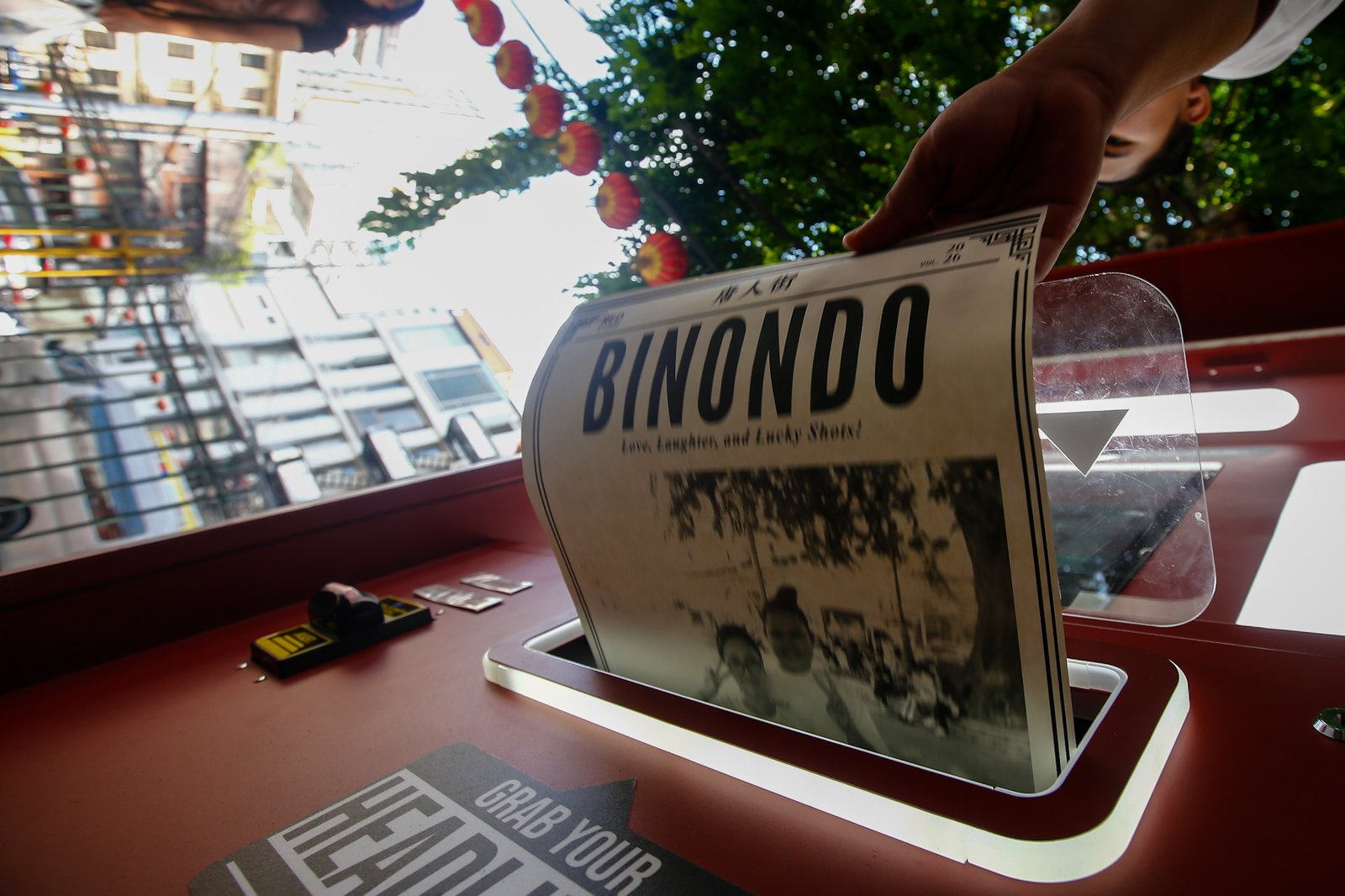 Tourists line up for a photo session at a booth in Plaza San Lorenzo Ruiz in Binondo, Manila on Saturday, 20 June 2026. The photo booth, which prints a vintage-style newspaper alongside a downloadable digital copy, is becoming a popular destination for Binondo-goers.