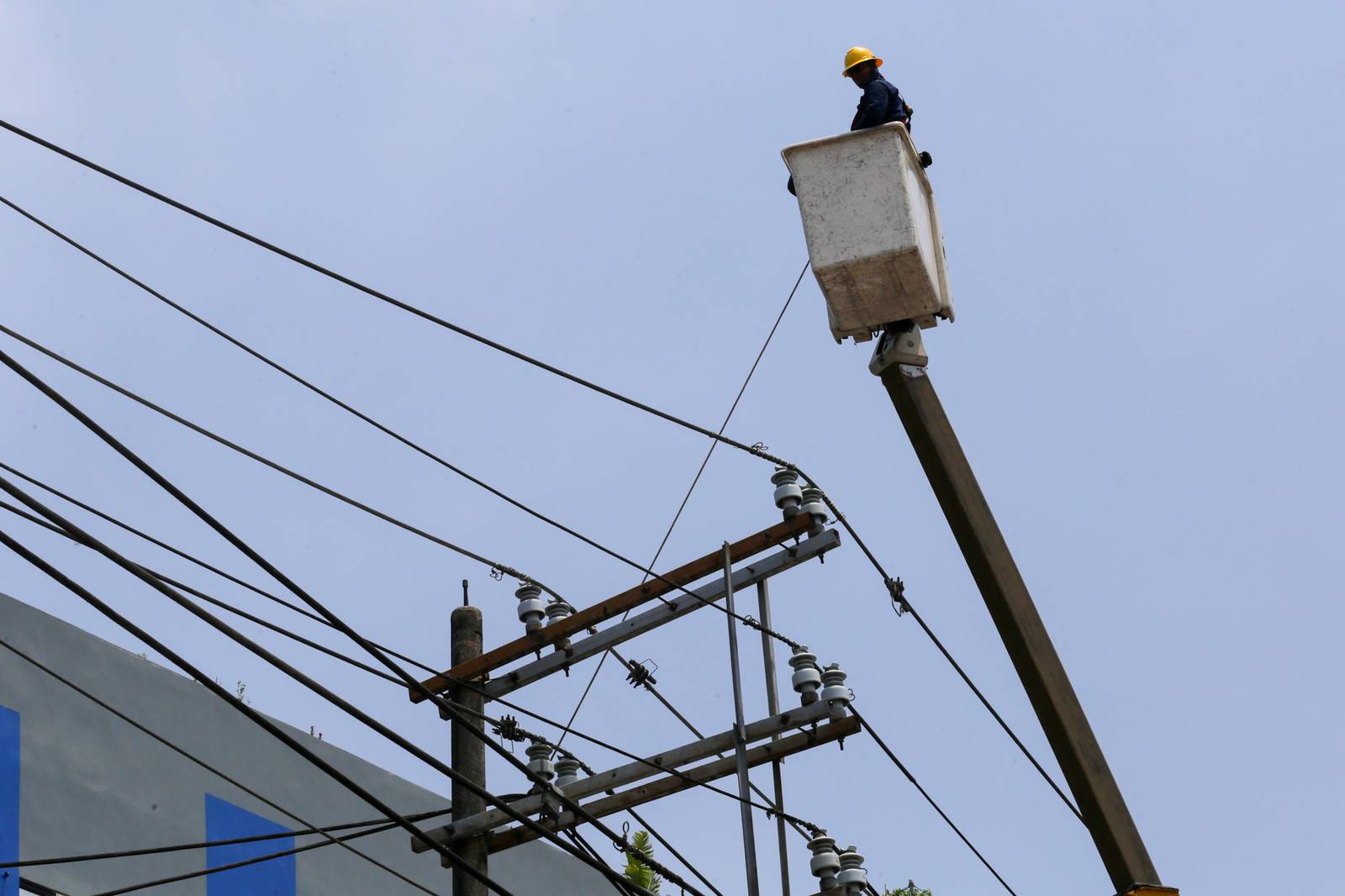 Workers from Meralco repair downed power lines in Malabon City on 22 June 2026, following a severe downpour the previous evening. Sudden strong winds and heavy rains caused three electrical posts to topple, cutting off electricity, phone lines, and internet services for local residents.
