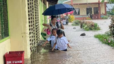CHILDREN of Panitian Elementary School in Sofronio Española, Palawan wade through waist-deep floodwaters after a sudden downpour inundated their campus on Monday, while a teacher races to save important school documents from the rising water.