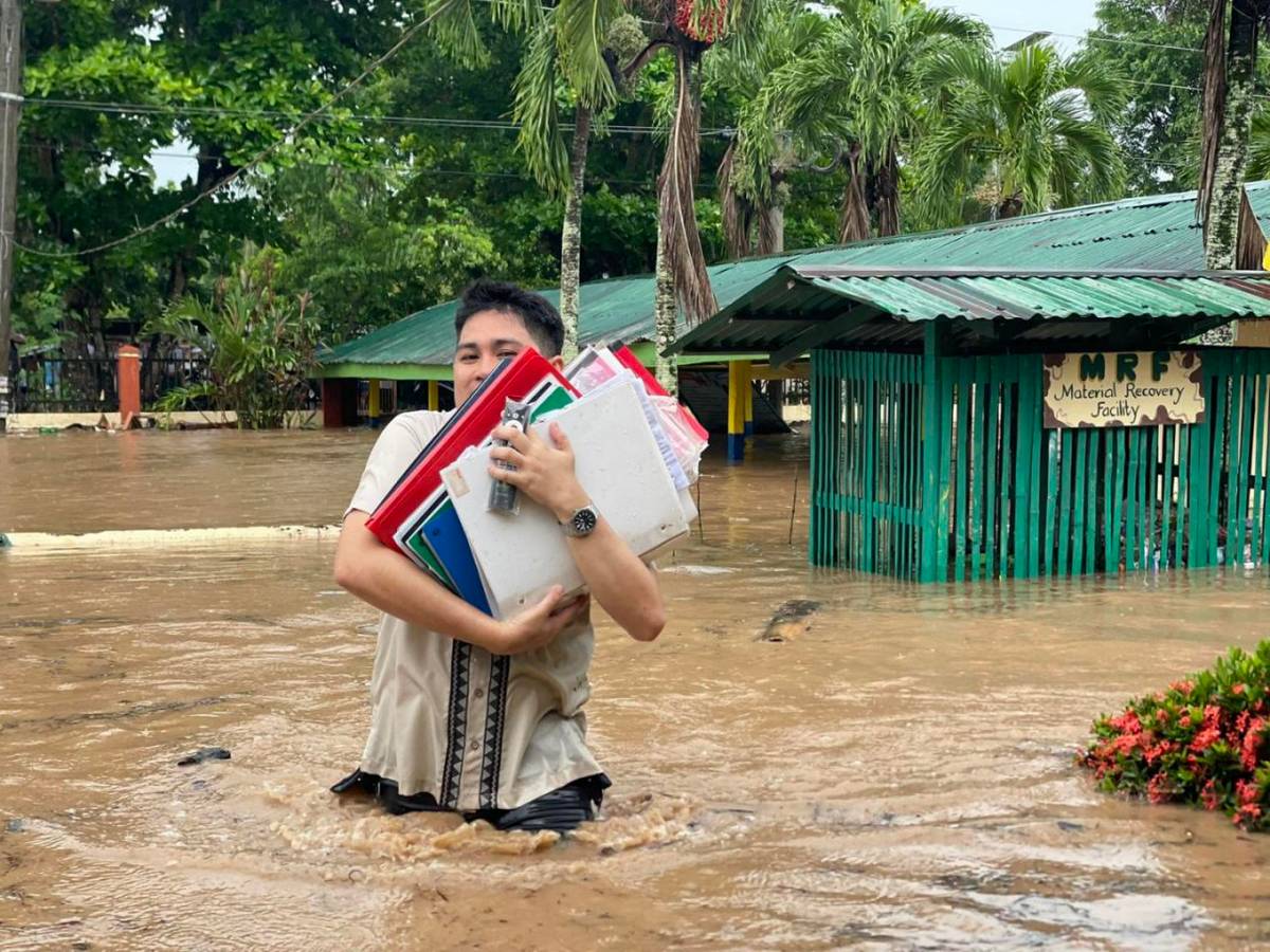CHILDREN of Panitian Elementary School in Sofronio Española, Palawan wade through waist-deep floodwaters after a sudden downpour inundated their campus on Monday, while a teacher races to save important school documents from the rising water.