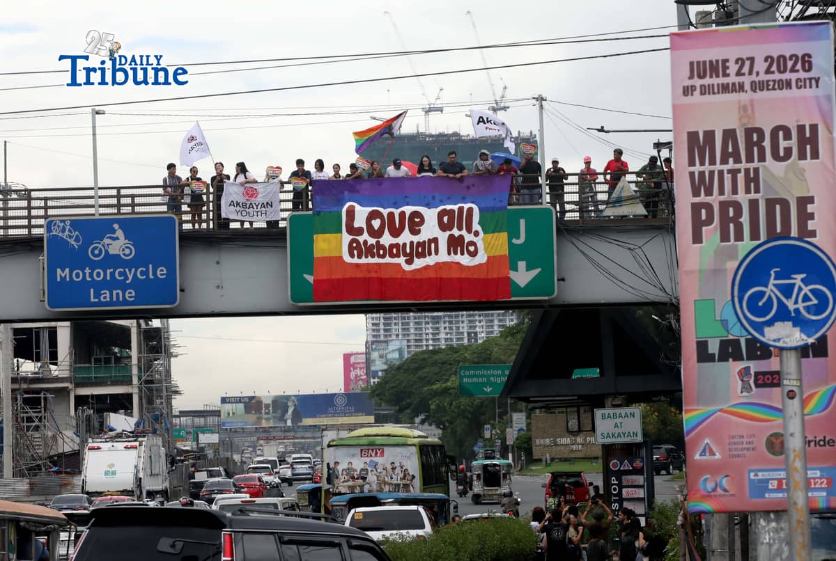 A day before the annual Pride March, volunteers from Akbayan Youth unfurl a rainbow banner reading, “Love All, Akbayan Mo! #PrideEquality,” on the Philcoa footbridge in Quezon City on Friday, calling for equality, dignity and recognition of every person's identity. | Photo by Analy Labor
