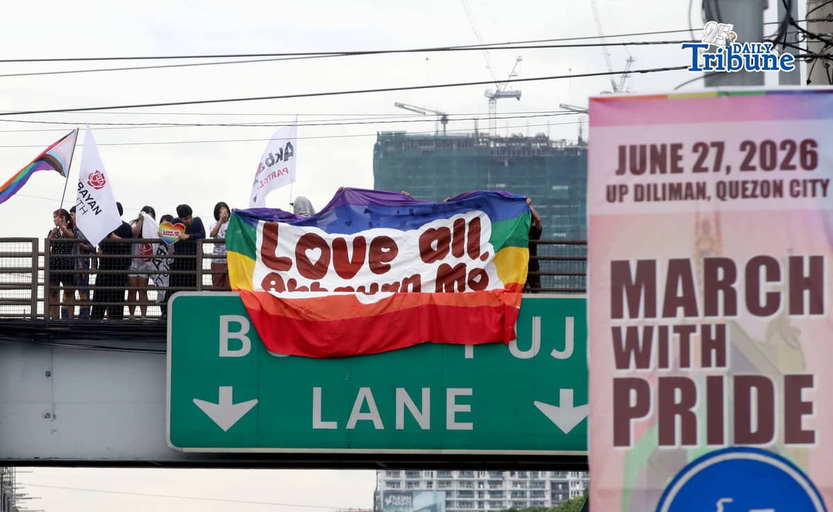 A day before the annual Pride March, volunteers from Akbayan Youth unfurl a rainbow banner reading, “Love All, Akbayan Mo! #PrideEquality,” on the Philcoa footbridge in Quezon City on Friday, calling for equality, dignity and recognition of every person's identity. | Photo by Analy Labor