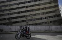 LOCALS ride a motorbike past a building damaged by a twin earthquake in Caraballeda, La Guaira state, about 40 kilometers northeast of Caracas, on 25 June 2026.