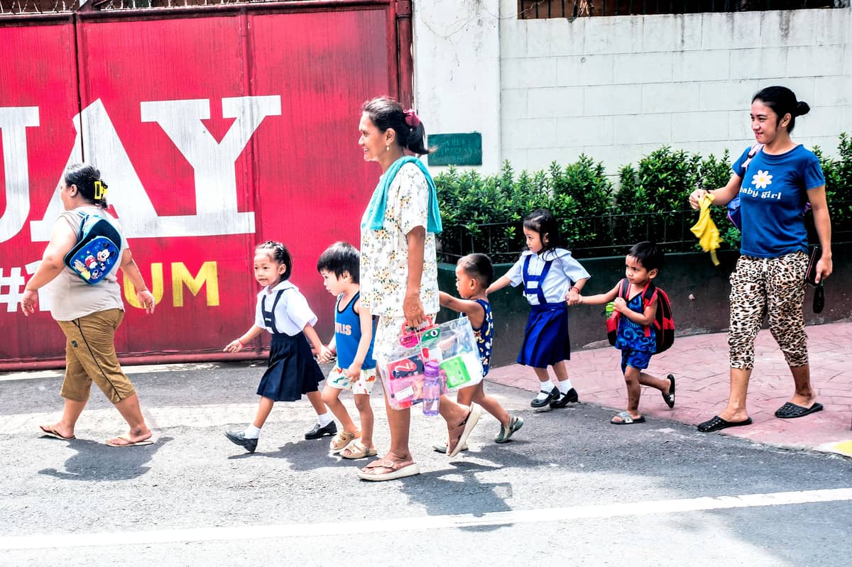 KINDERGARTEN students and their mothers traverse Quiapo, Manila, on the first day of classes.