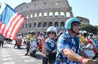 VESPA enthusiasts wave a United States flag as they ride during the parade of the Vespa World Days marking the 80th anniversary of the iconic Italian brand of scooters in Rome on 27 June 2026.