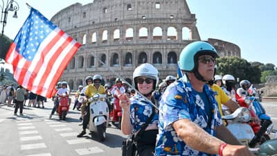 VESPA enthusiasts wave a United States flag as they ride during the parade of the Vespa World Days marking the 80th anniversary of the iconic Italian brand of scooters in Rome on 27 June 2026.