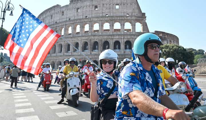 VESPA enthusiasts wave a United States flag as they ride during the parade of the Vespa World Days marking the 80th anniversary of the iconic Italian brand of scooters in Rome on 27 June 2026.