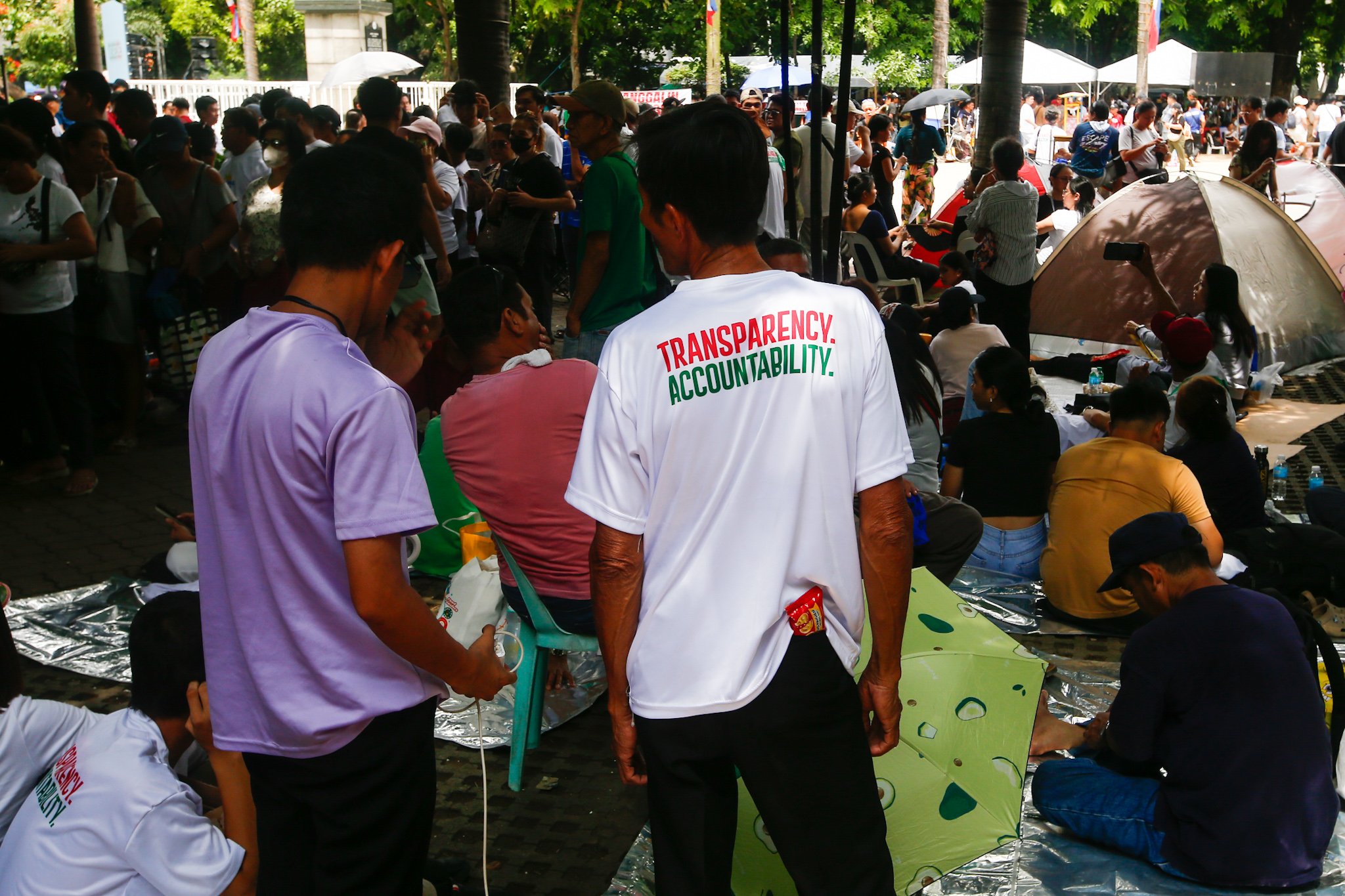 Members of Iglesia ni Cristo and their allies seek shade under trees at Liwasang Bonifacio in Manila on 02 July 2026 as they wait for the start of their protest rally. The organizers relocated the rally from the EDSA People Power Monument in Quezon City after their permit to hold the event there was revoked.
