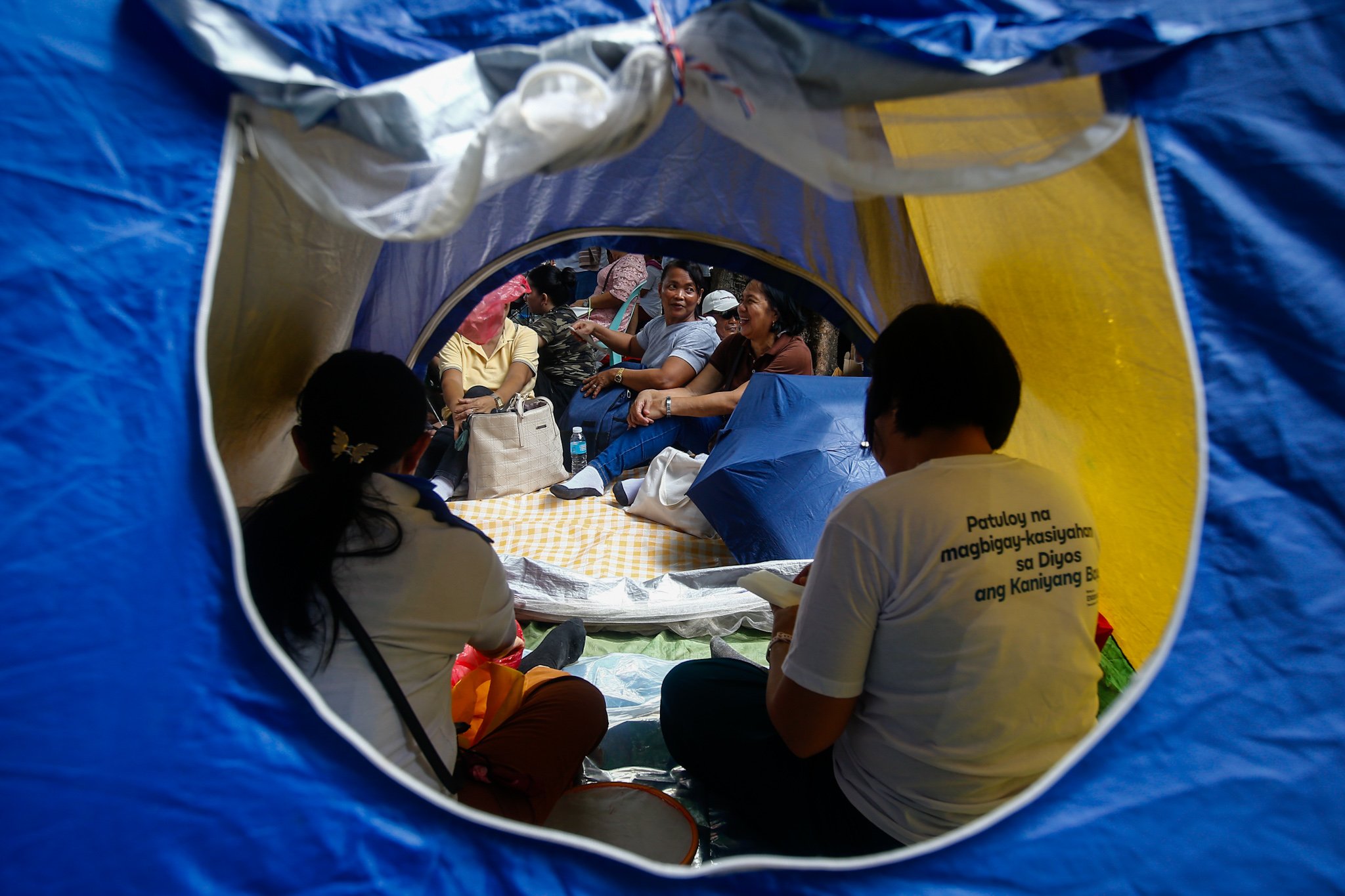 Members of Iglesia ni Cristo and their allies seek shade under trees at Liwasang Bonifacio in Manila on 02 July 2026 as they wait for the start of their protest rally. The organizers relocated the rally from the EDSA People Power Monument in Quezon City after their permit to hold the event there was revoked.