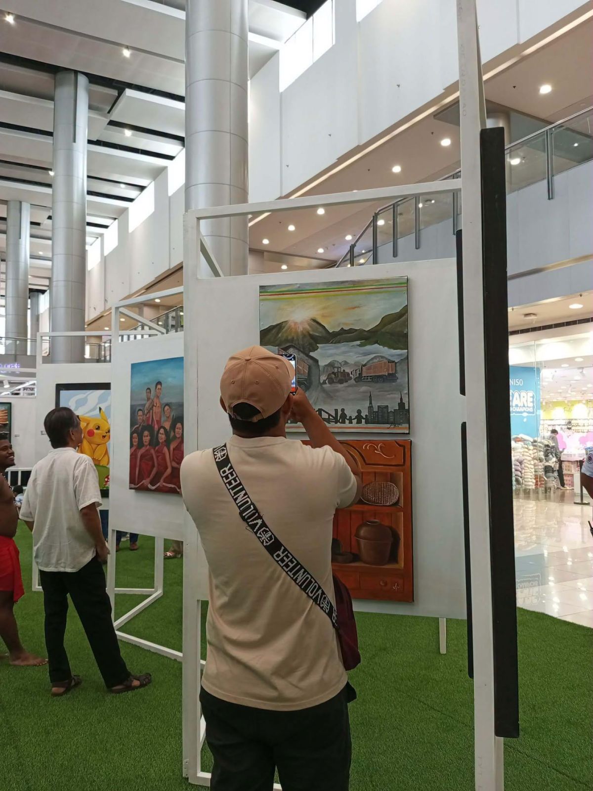 A visitor photographs artworks on display.
