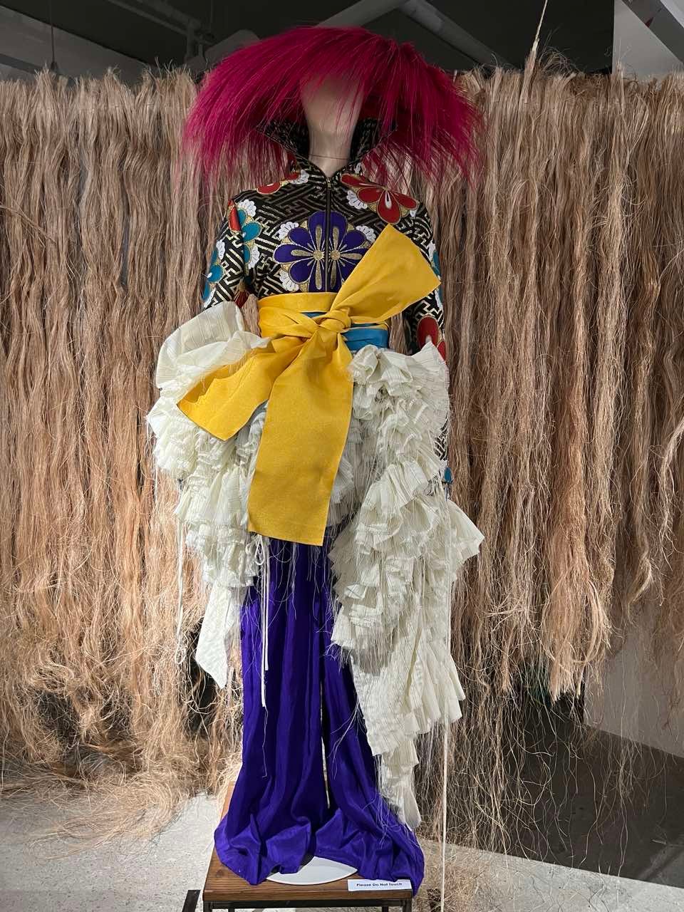 A cropped tailored obi jacket with structural sleeves, deconstructed tiered linen dress, and silk taffeta trousers with walis tambo headpiece, obi sash belt and velvet pumps by Jaggy Glarino.