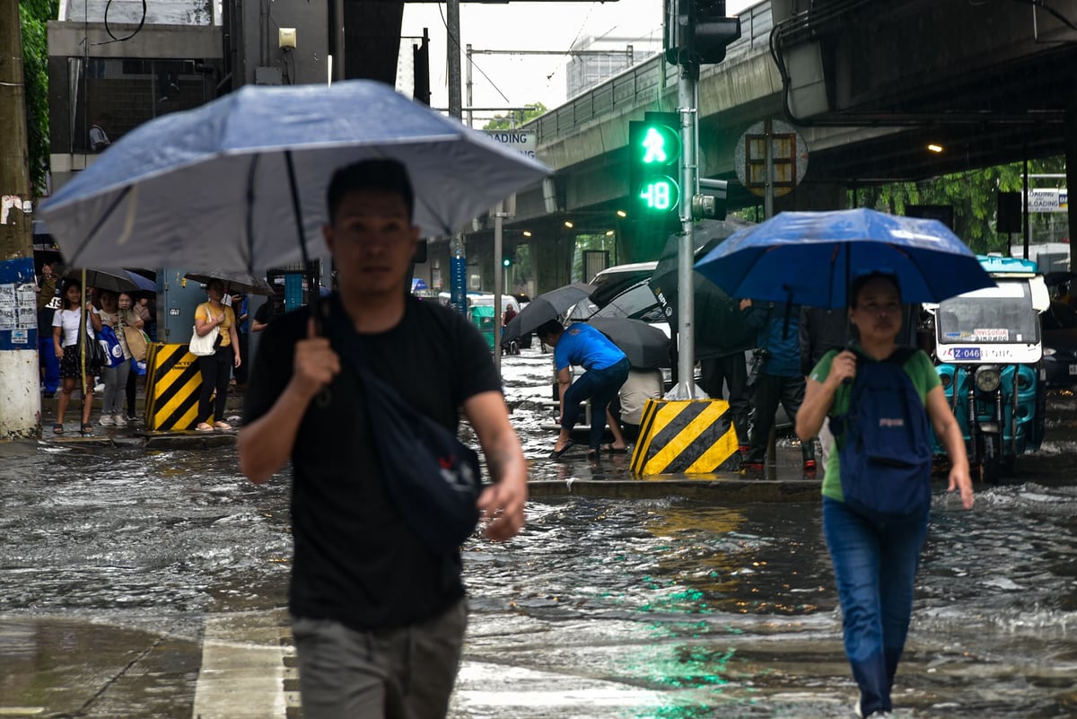 Pedestrian wade through gutter-deep flood in Manila, on July 10