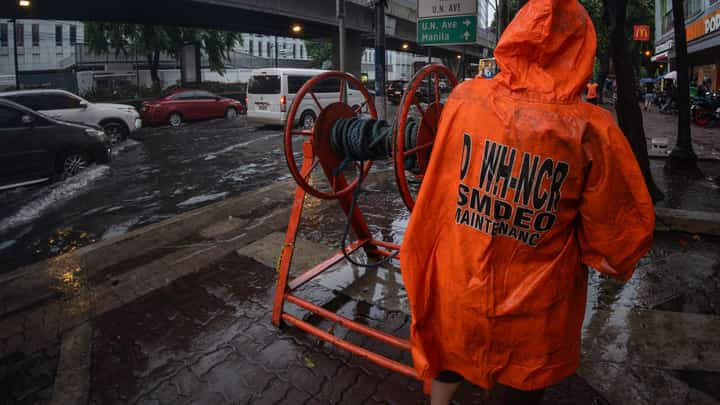 Department of Public Works and Highways personnel declog a portion of Taft Avenue in Manila on Friday after a sudden downpour brought by the southwest monsoon, enhanced by Typhoon Inday, caused flooding.