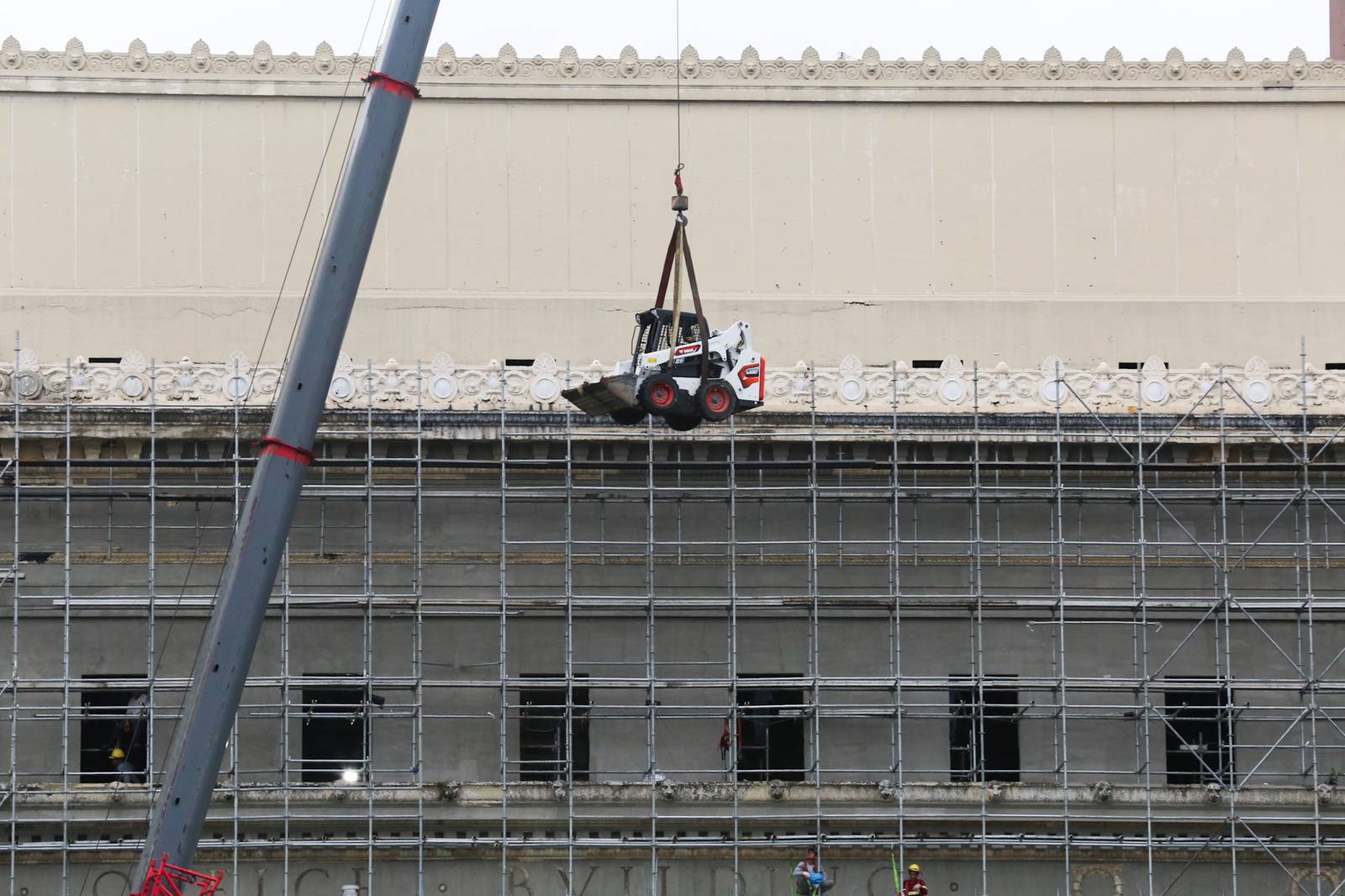 A crane lifts a mini pail loader onto the roof of the Manila Central Post Office at Liwasang Bonifacio in Manila. The century-old Neoclassical landmark, designed by architects Juan M. Arellano, Tomás Mapúa, and Ralph Doane, is undergoing extensive repairs and renovation after a major fire severely damaged the building two years ago.