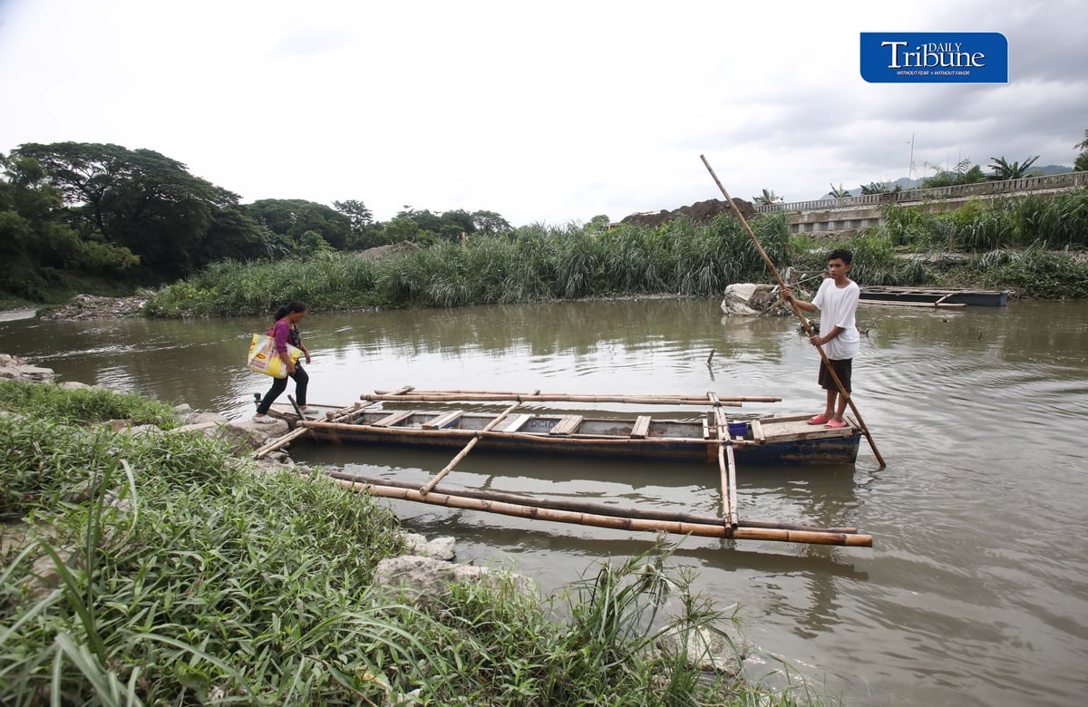 (July 11, 2026) A woman from Brgy. Bagong Silangan in Quezon City rides a small boat on Friday, paying a P10 fare to cross the river to San Mateo, Rizal.
Photo / Analy Labor