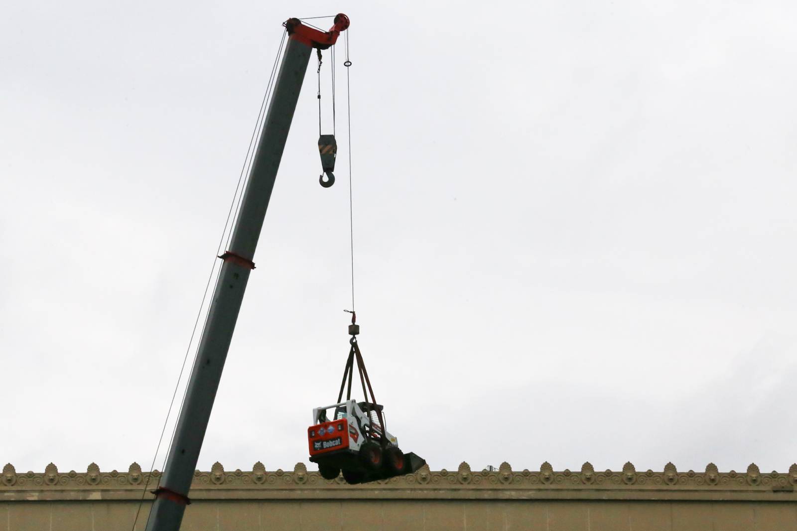 A crane lifts a mini pail loader onto the roof of the Manila Central Post Office at Liwasang Bonifacio in Manila. The century-old Neoclassical landmark, designed by architects Juan M. Arellano, Tomás Mapúa, and Ralph Doane, is undergoing extensive repairs and renovation after a major fire severely damaged the building two years ago.