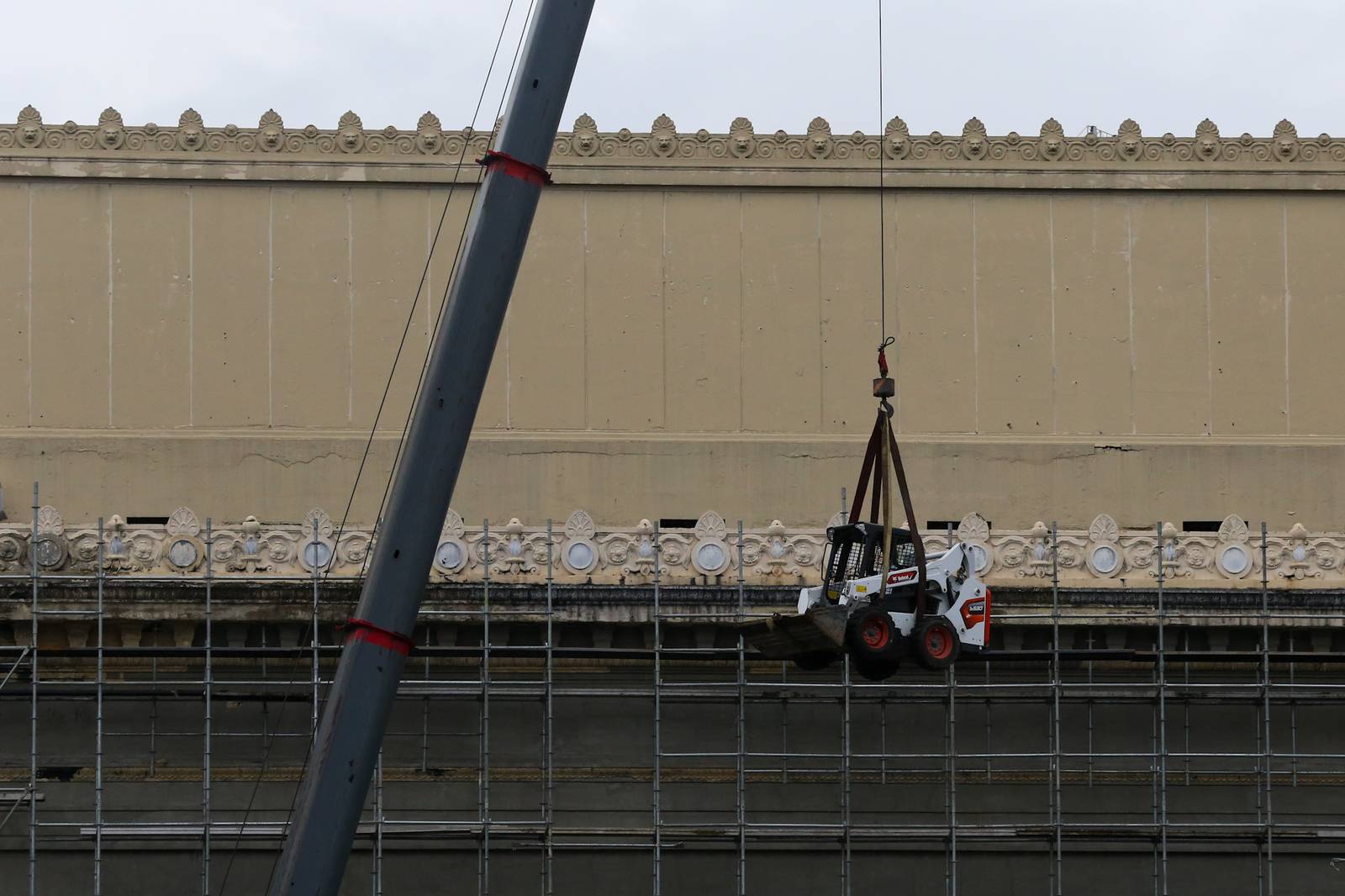 A crane lifts a mini pail loader onto the roof of the Manila Central Post Office at Liwasang Bonifacio in Manila. The century-old Neoclassical landmark, designed by architects Juan M. Arellano, Tomás Mapúa, and Ralph Doane, is undergoing extensive repairs and renovation after a major fire severely damaged the building two years ago.