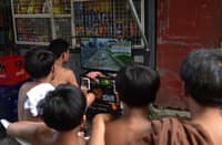 TEENAGERS crowd around a makeshift, pay-to-play gaming station in Manila. Neighborhood gaming setups provide affordable entertainment for local youths in many residential areas across the capital city.