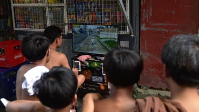 TEENAGERS crowd around a makeshift, pay-to-play gaming station in Manila. Neighborhood gaming setups provide affordable entertainment for local youths in many residential areas across the capital city.