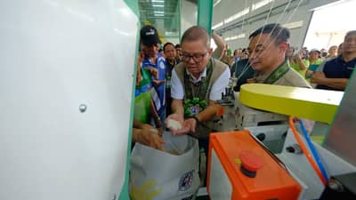 Agriculture Secretary Francisco P. Tiu Laurel Jr. inspects freshly milled rice during the inauguration of the National Food Authority's new P355.4-million integrated grains facility in Dumangas, Iloilo, a project designed to expand palay procurement, improve post-harvest handling, and strengthen the country's rice buffer stock.