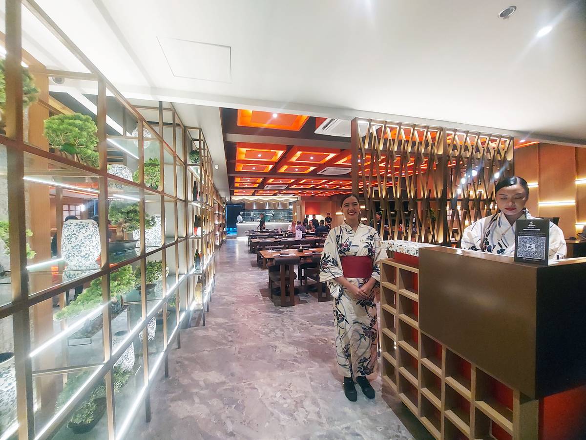 Guests are welcomed by ladies in kimono and a bonsai wall.